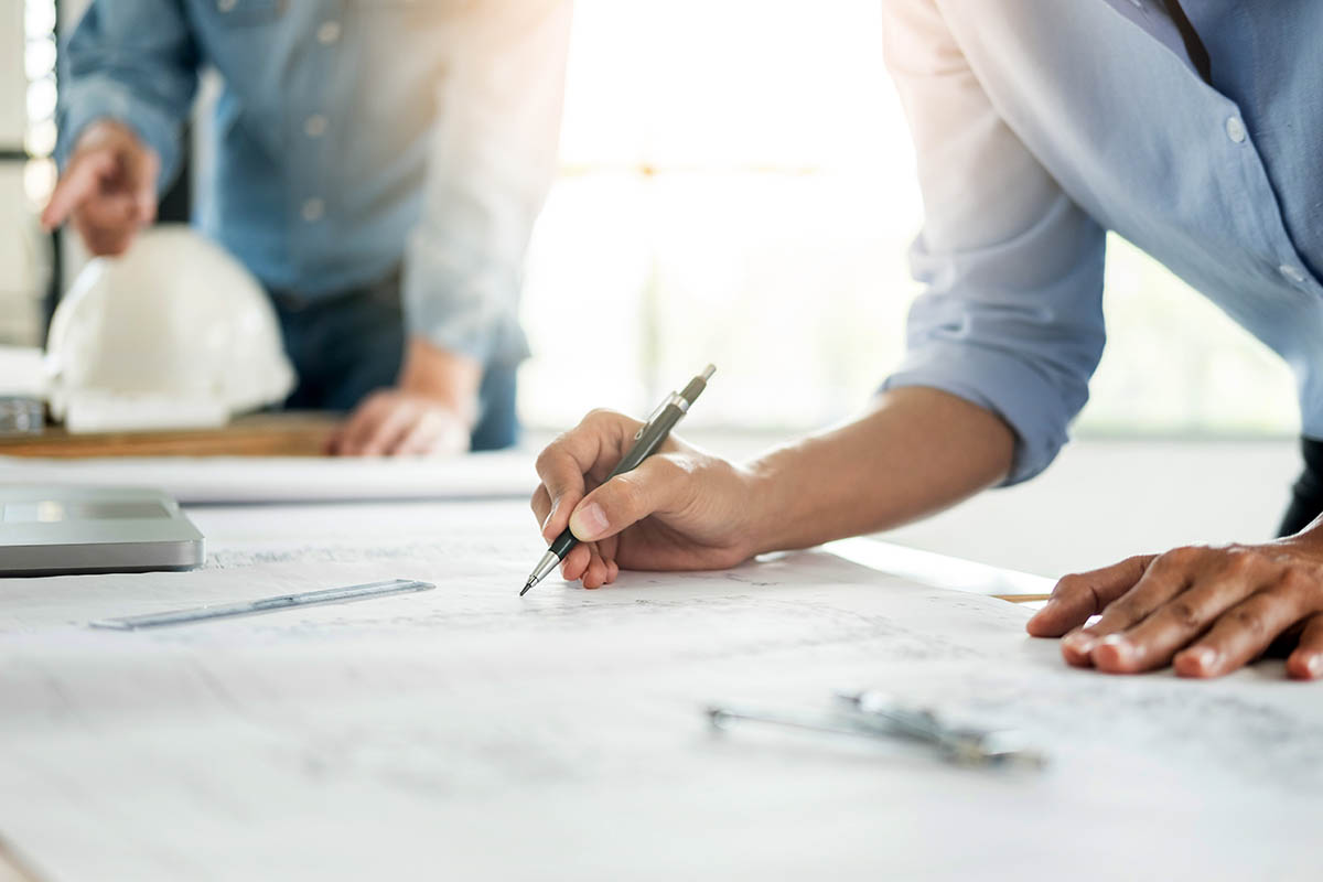 Close-up Of Person's engineer Hand Drawing Plan On Blue Print with architect equipment, Architects discussing at the table, team work and work flow construction concept.